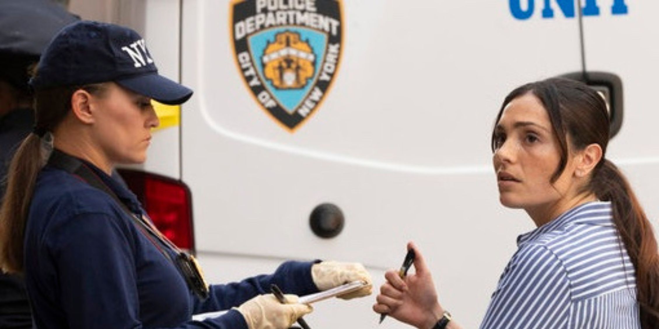 Silva standing by a CSU truck holding a pen and talking to a woman with an NYPD cap