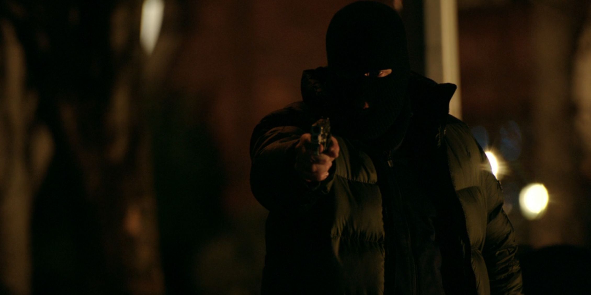 Blue Bloods a masked gunman pointing his gun on a dark street