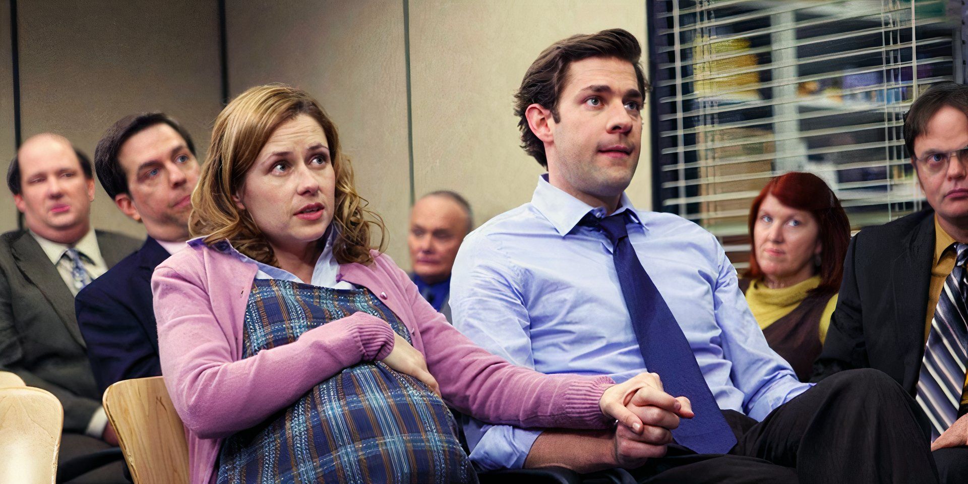 A pregnant Pam holds Jim's hand in the meeting room in The Office