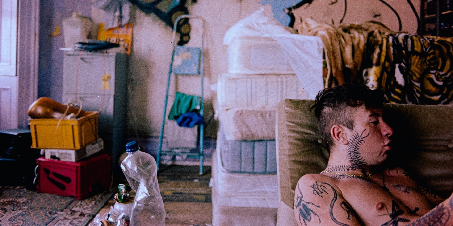 A tattooed Barry Keoghan lounging on a chair in Bird