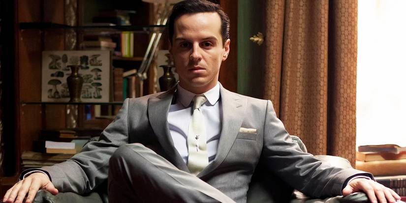 Andrew Scott sitting in a chair with his legs crossed as Moriarty in Sherlock