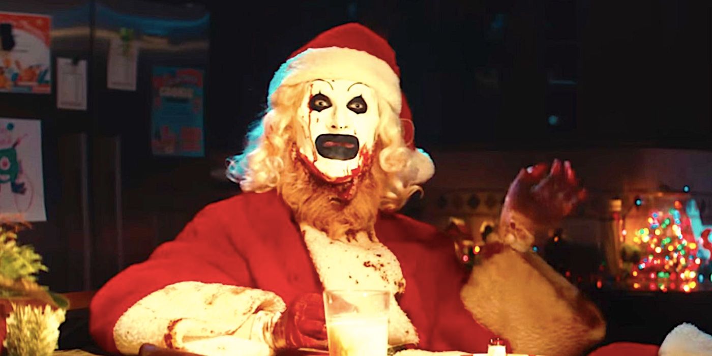 Art the Clown sits at kitchen table dressed as Santa with milk and cookies in Terrifier 3