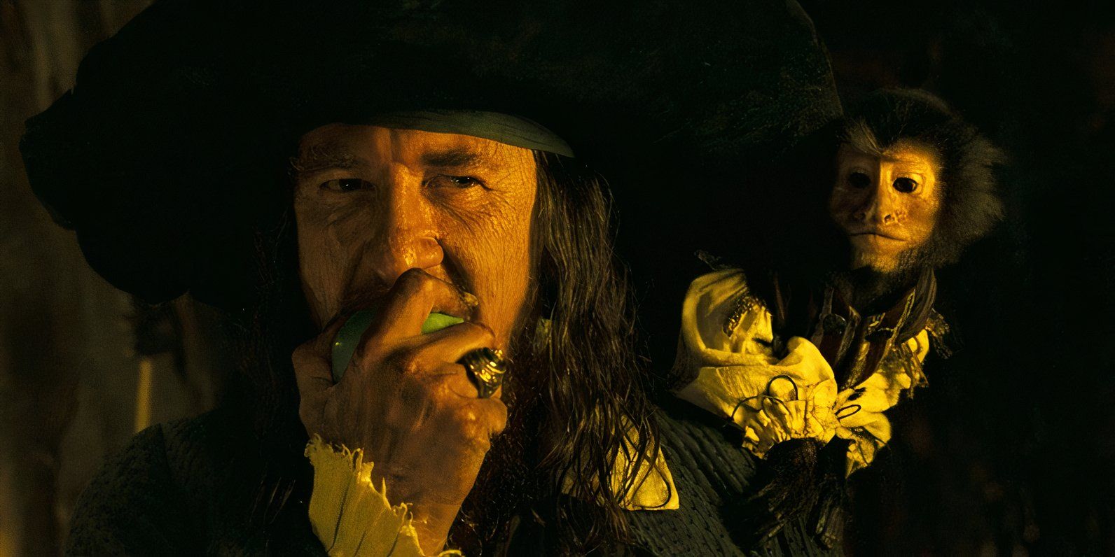 Captain Barbossa (Geoffrey Rush) biting into an apple with the monkey on his shoulder at the end of Pirates of the Caribbean: Dead Man's Chest