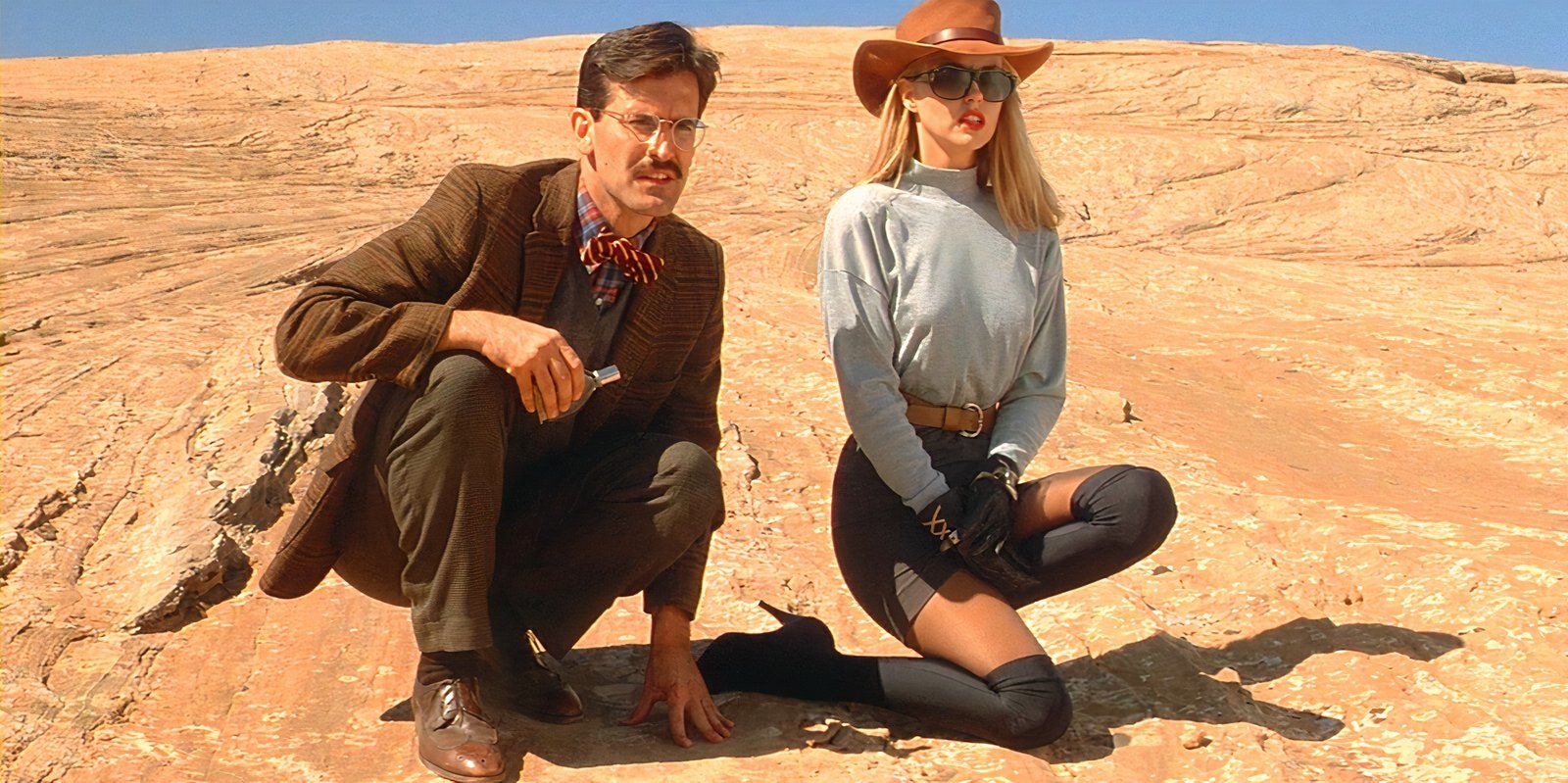 Bruce Campbell and Deborah Foreman kneeling in the desert in sundown: the vampire in retreat