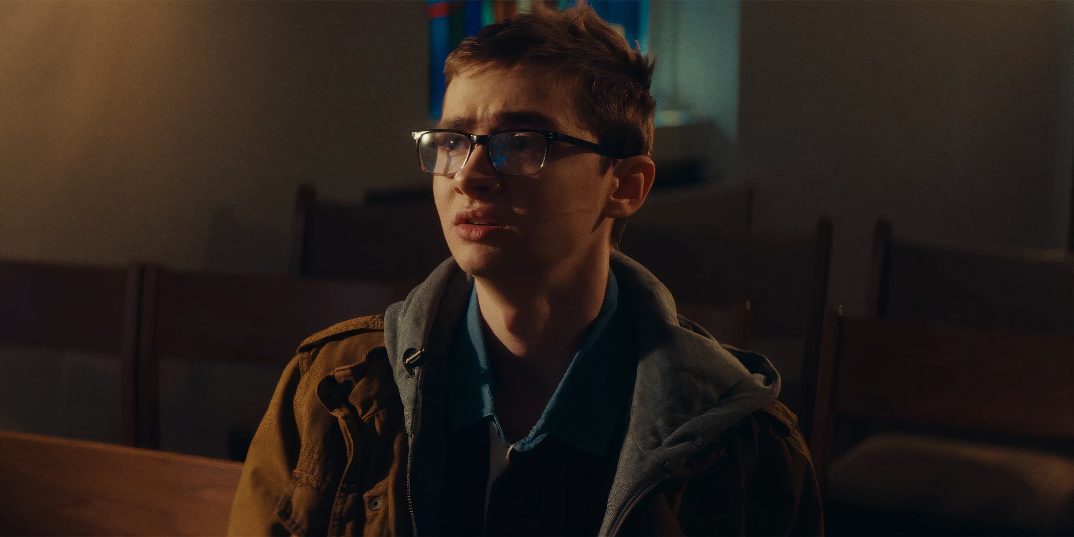 Elliot Fullam as Jonathan looking scared while sitting down in a church in Terrifier 3