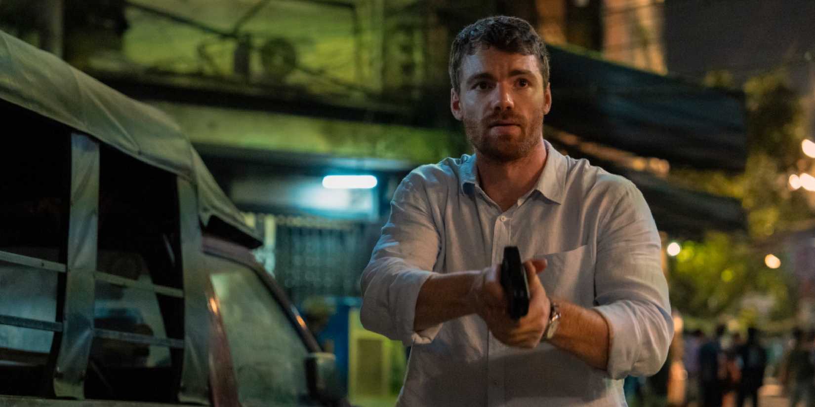 Gabriel Basso as Peter Sutherland holding a gun in The Night Agent season 2