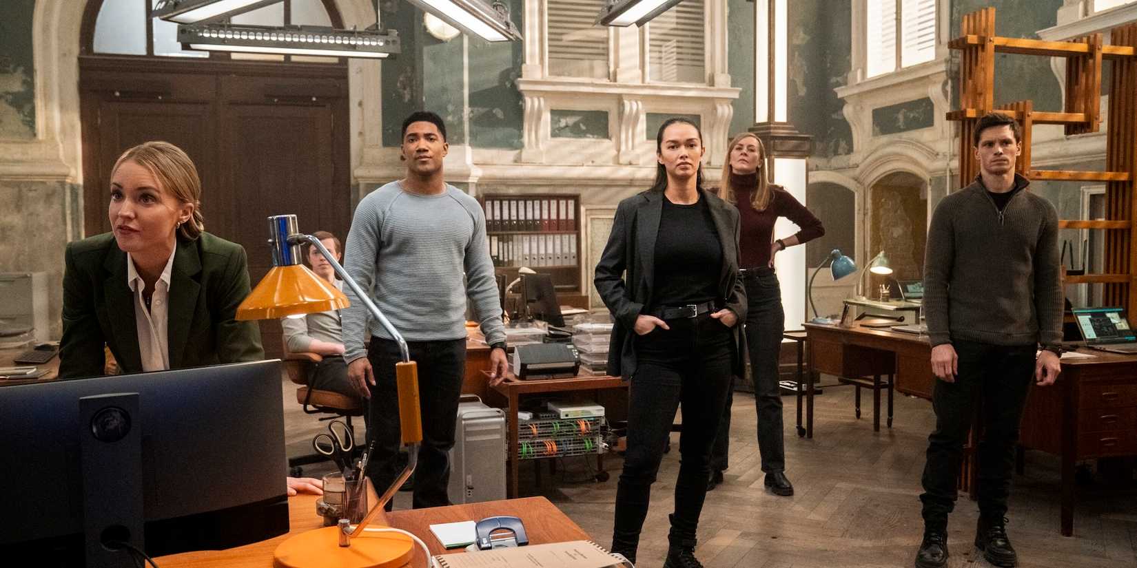 The cast of FBI International standing in their Budapest headquarters