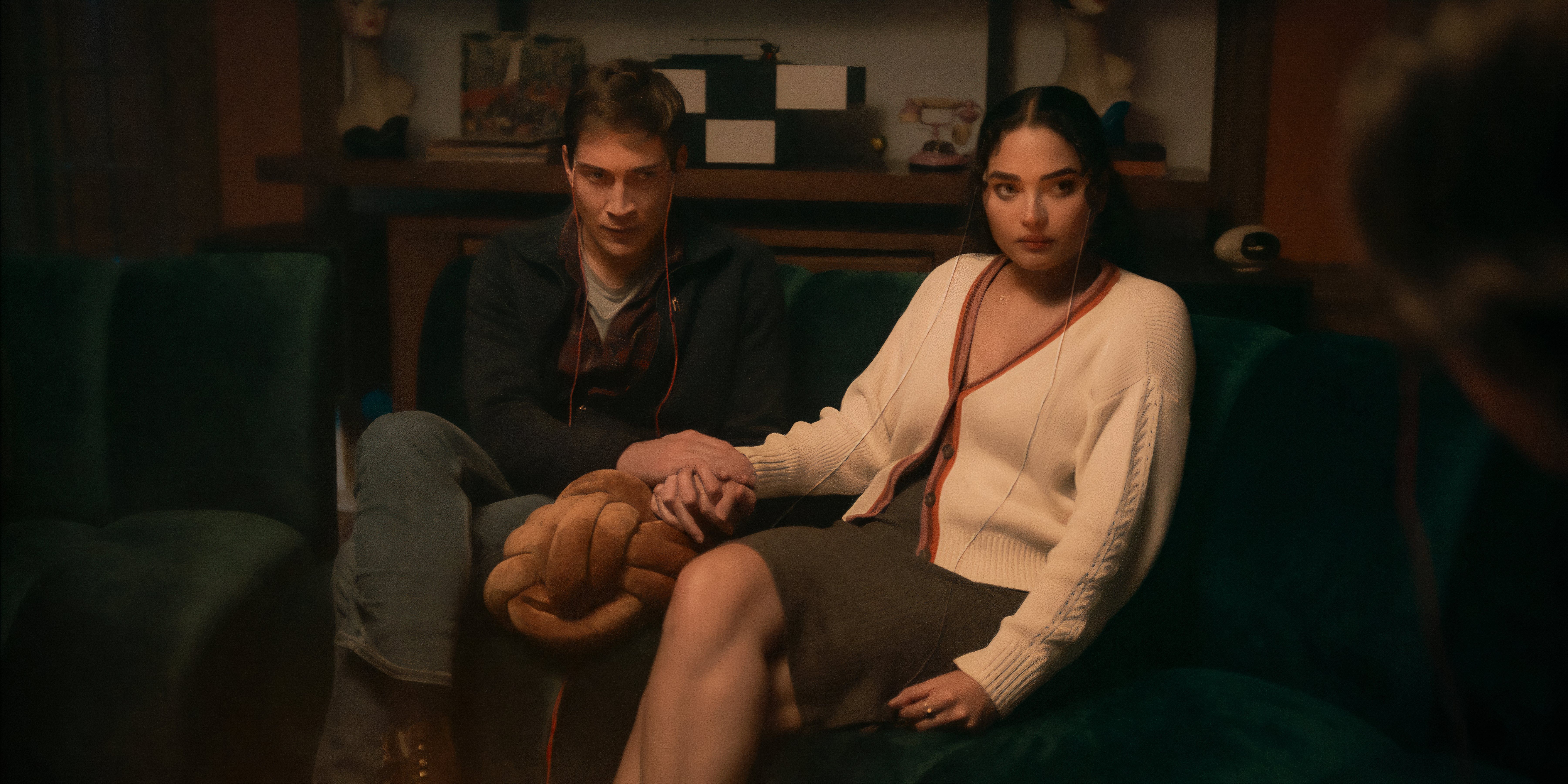 Shelby and Cyrus hold hands while sitting on the couch in Netflix's It's What's Inside.