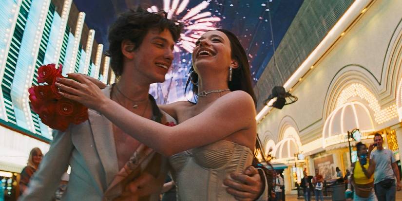Ivan and Anora hugging while walking around in Vegas with fireworks in the background in Anora-1