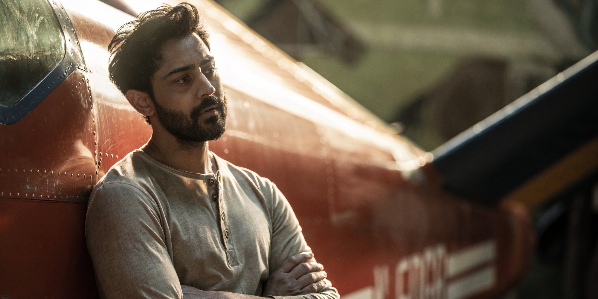 Manish Dayal as Ash leaning against his plane in The Walking Dead Daryl Dixon season 2