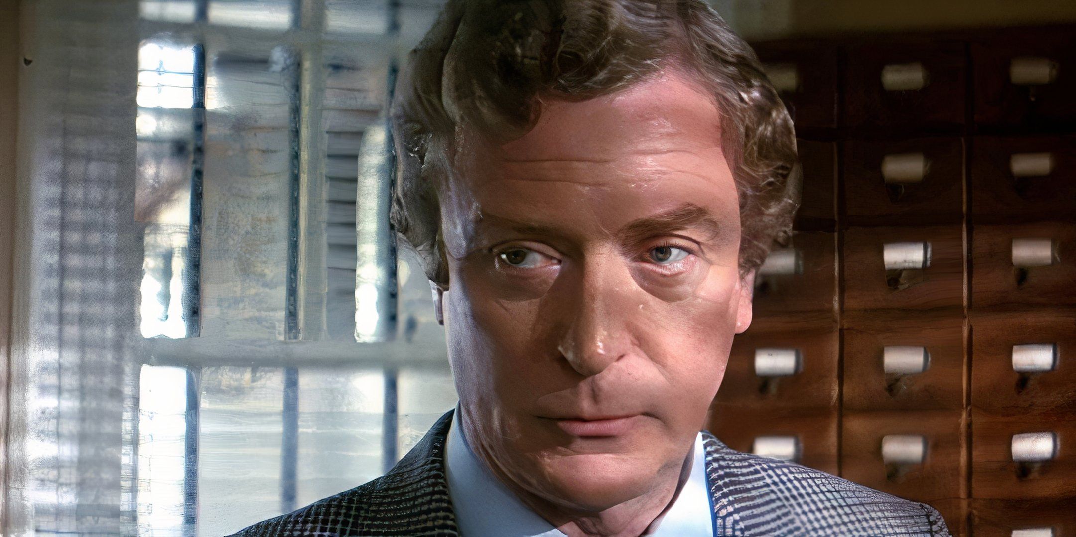 Michael Caine looks to the side with a serious expression on his face. 