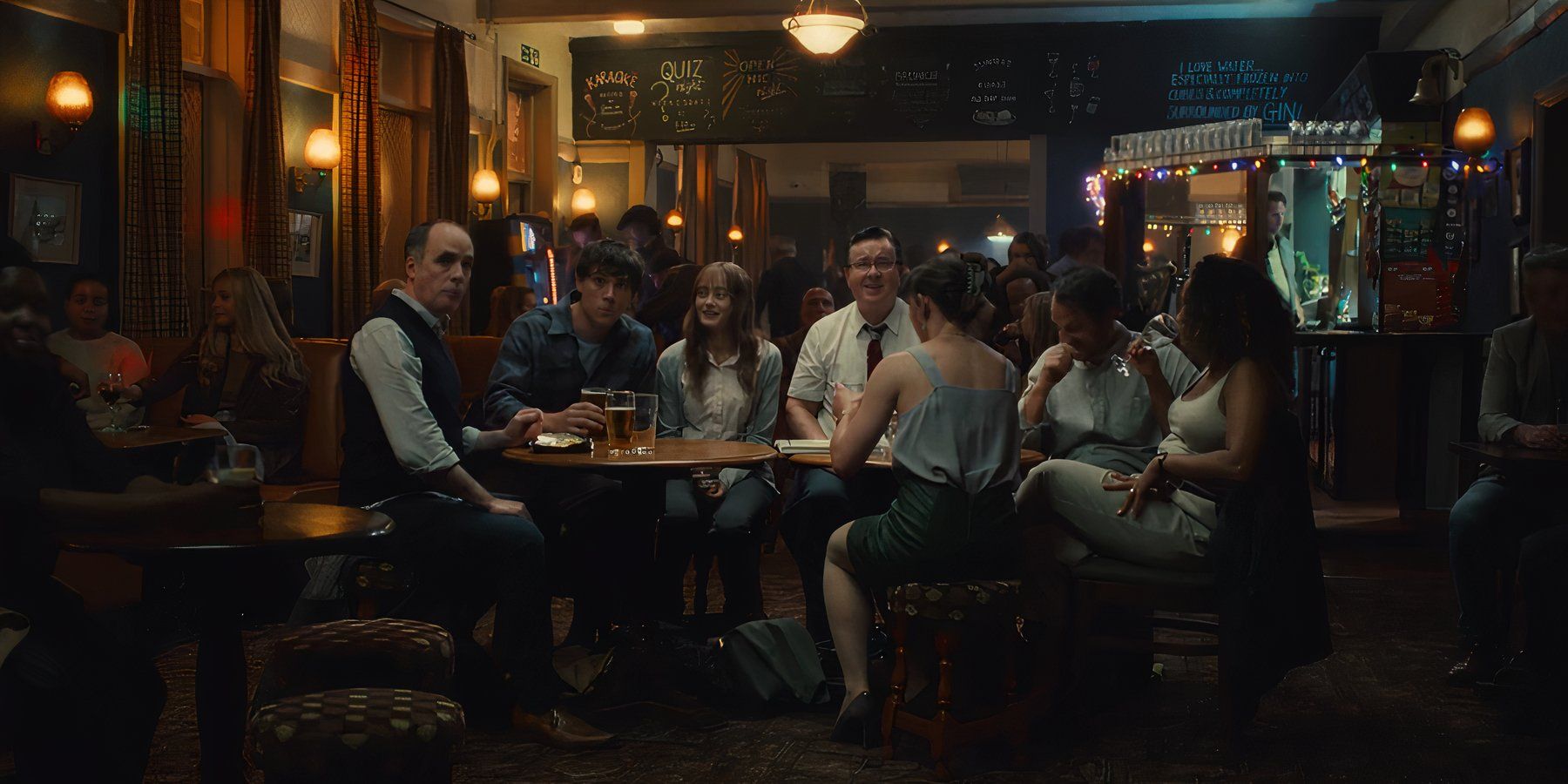 Rhiannon (Ella Purnell) sitting with her workmates in a pub in Sweetpea episode 2