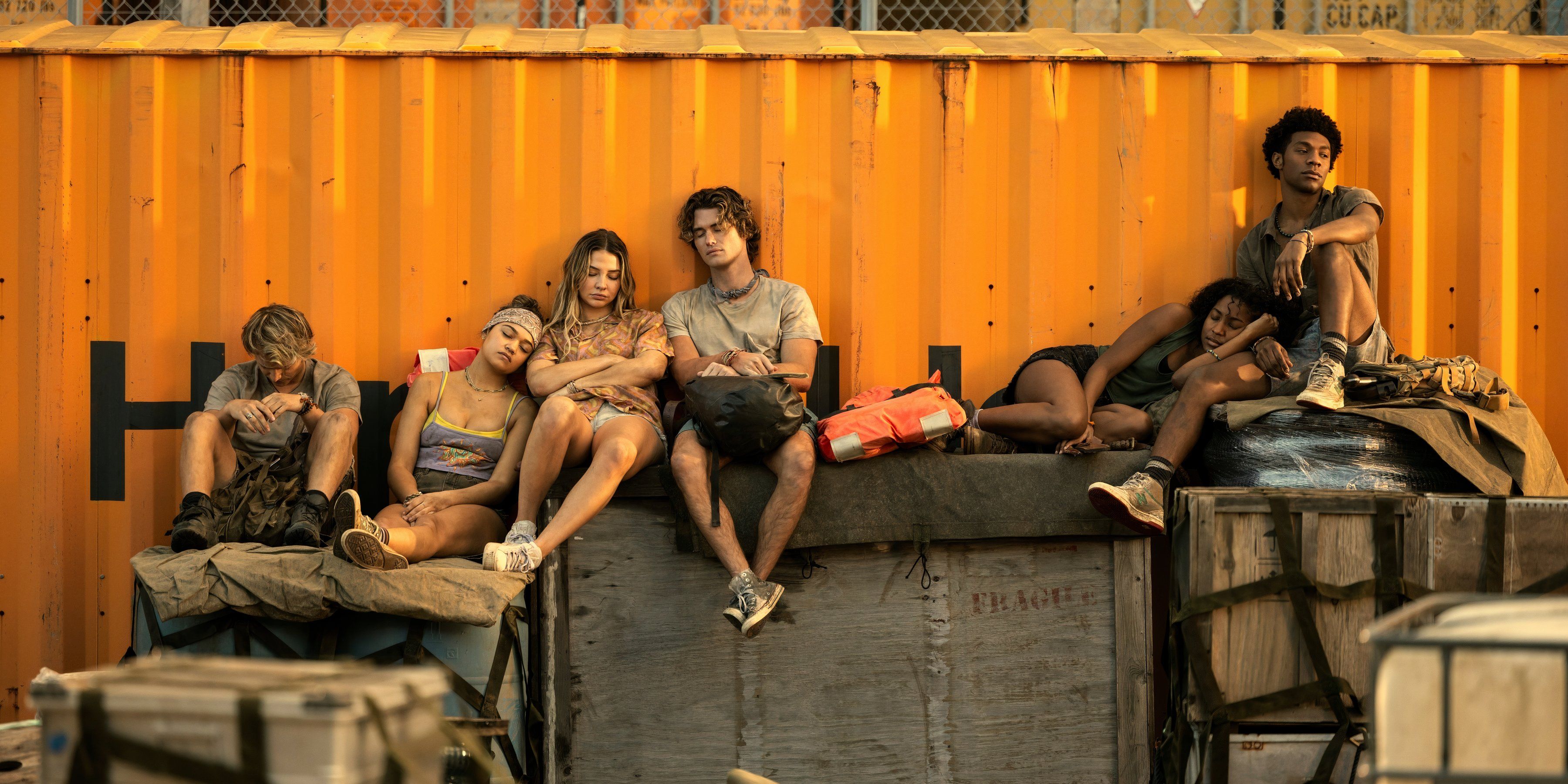 Rudy Pankow, Madison Bailey, Madelyn Cline, Chase Stokes, Carlacia Grant, Jonathan Daviss sit on a crate in Outer Banks season 4