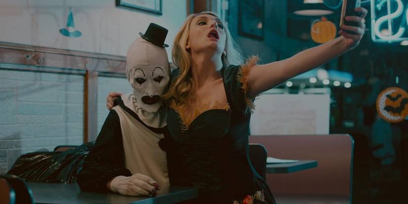 Woman sits on Art the Clown in Terrifier (2016).