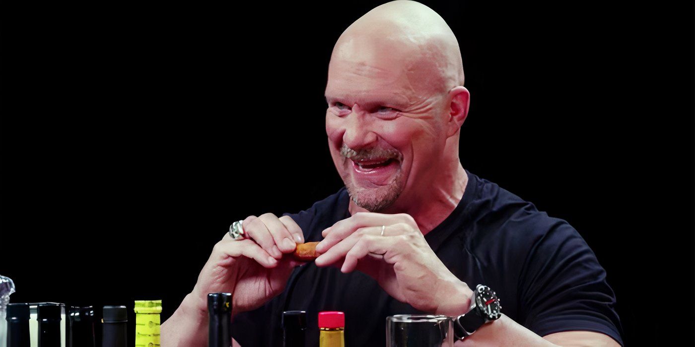 Stone Cold Steve Austin smiling while eating wings on Hot Ones