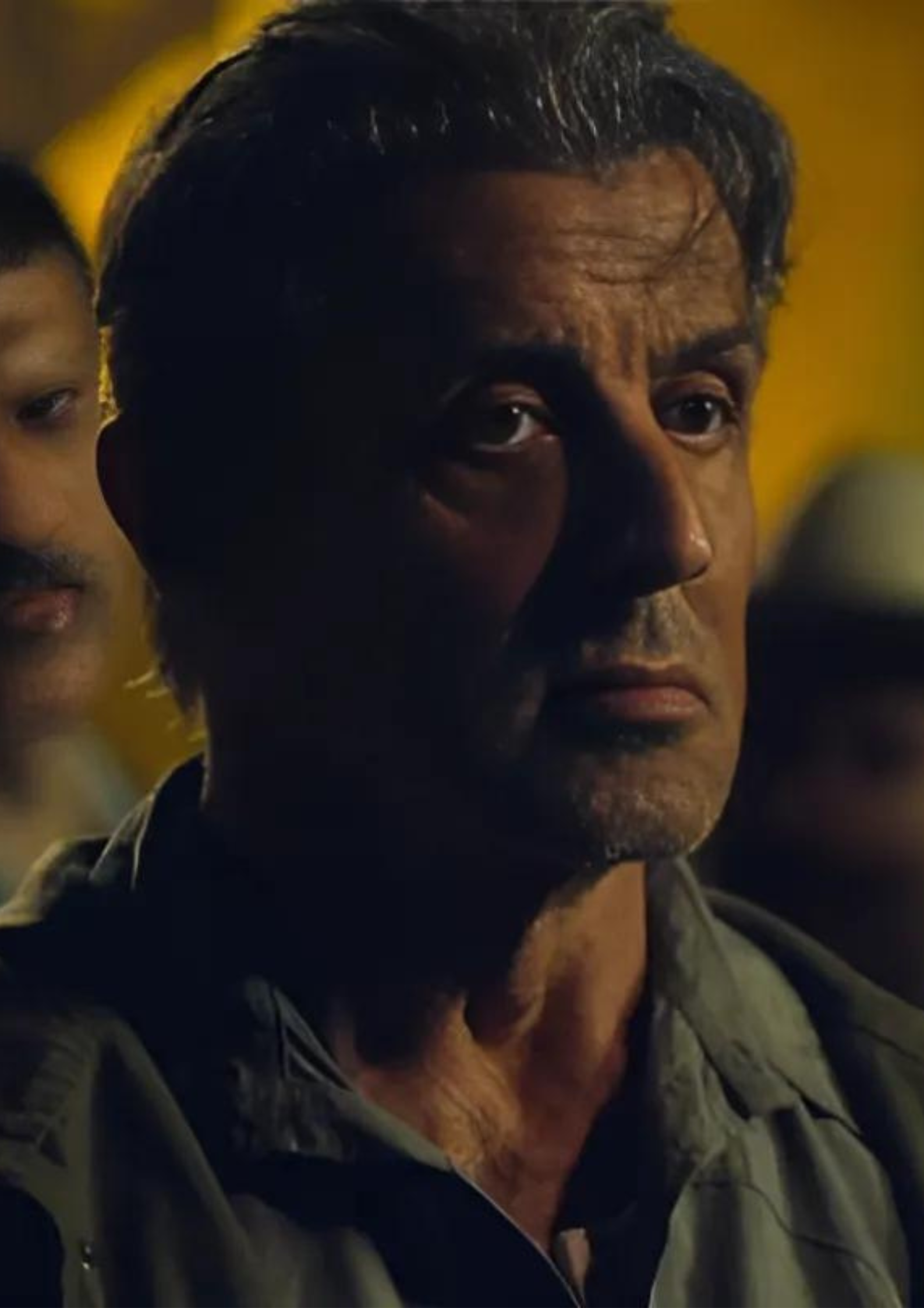 Sylvester Stallone as John Rambo in Rambo Last Blood (2019) surrounded by men