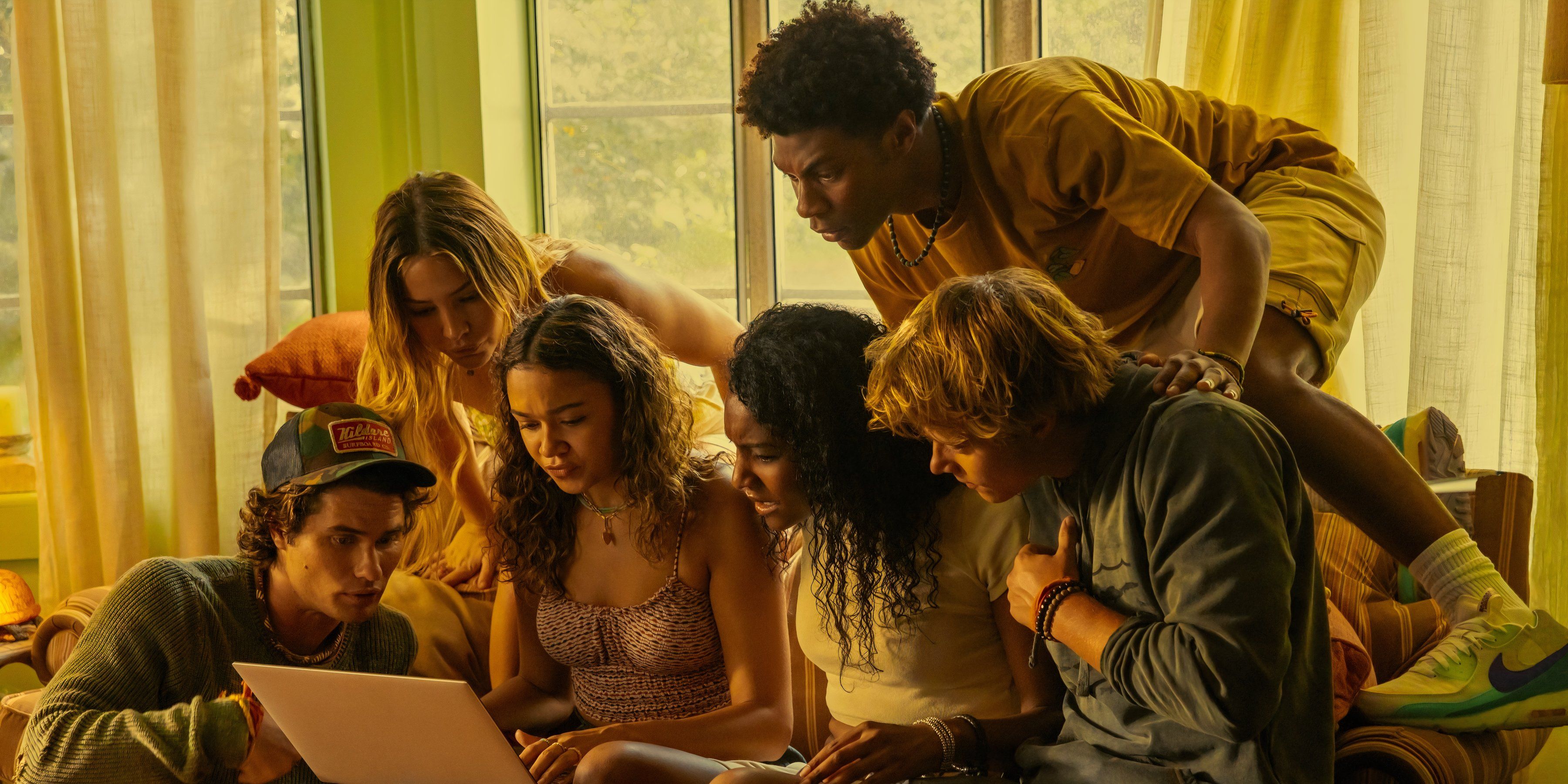 The cast of Outer Banks looks at a laptop in season 4