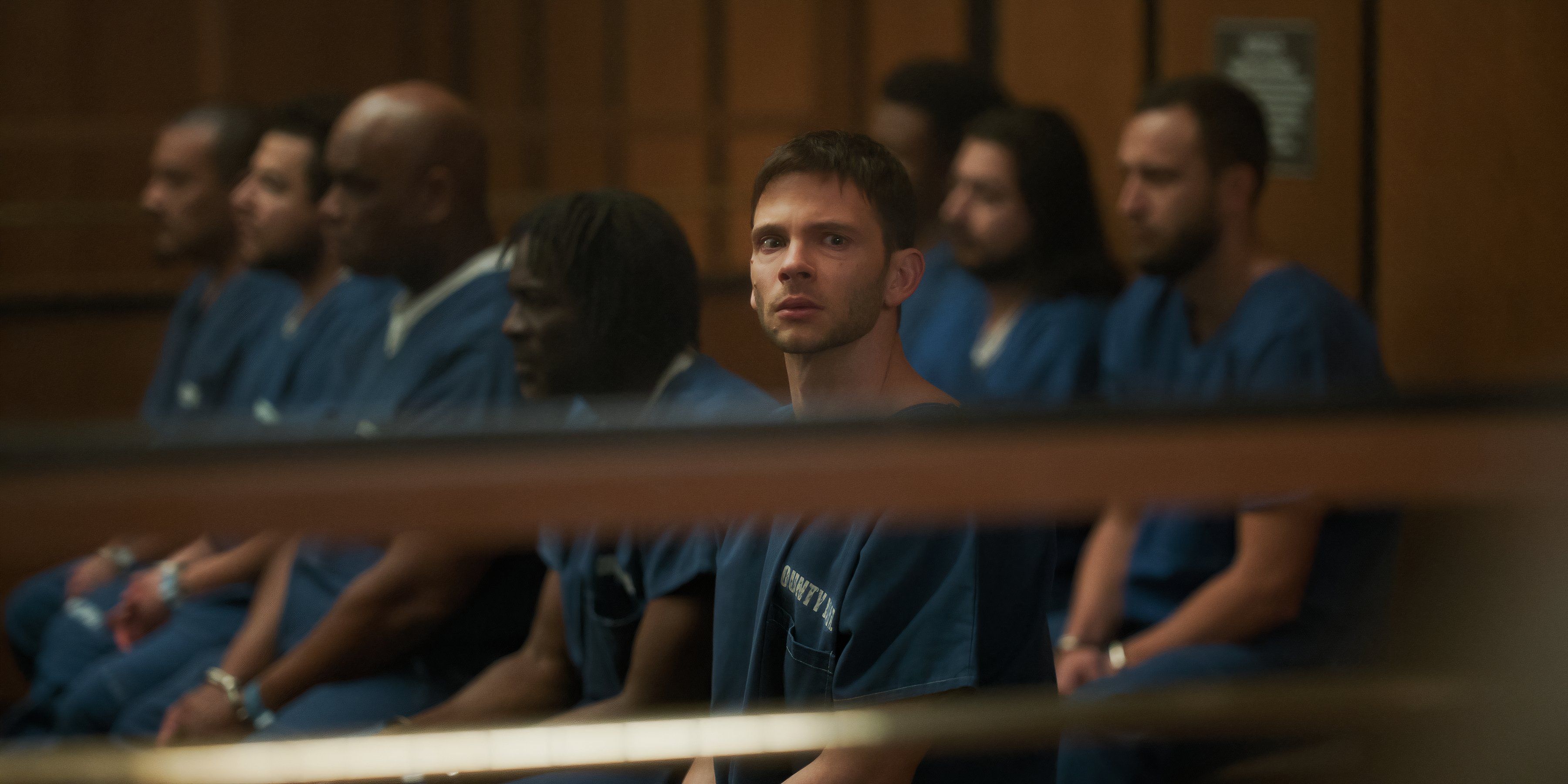 Julian sits with the other inmates in The Lincoln Lawyer season 3 episode 2.