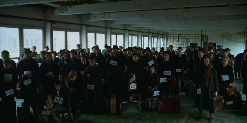 A crowd with numbers and suitcases in The Brualist