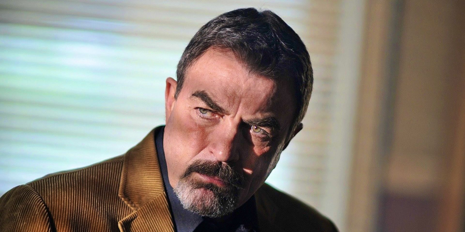 Tom Selleck como Jesse Stone piensa con la luz brillando sobre él a través de las cortinas.