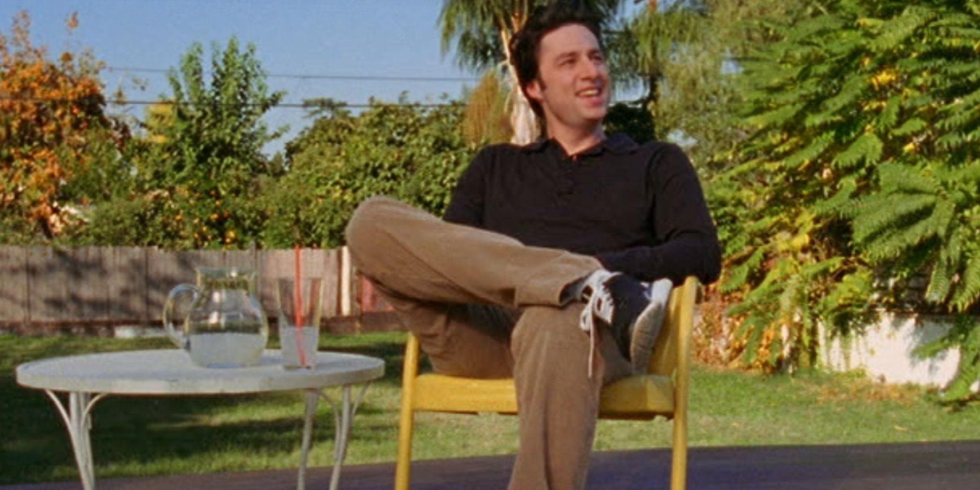 Zach Braff smiling as JD as he sits on his deck in Scrubs