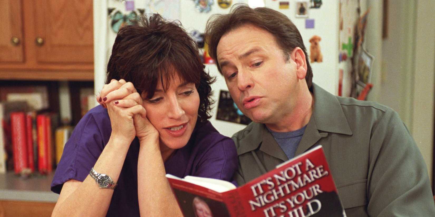 Katey Sagal as Cate Hennessy and John Ritter as Paul Hennessy reading a book together in 8 Simple Rules