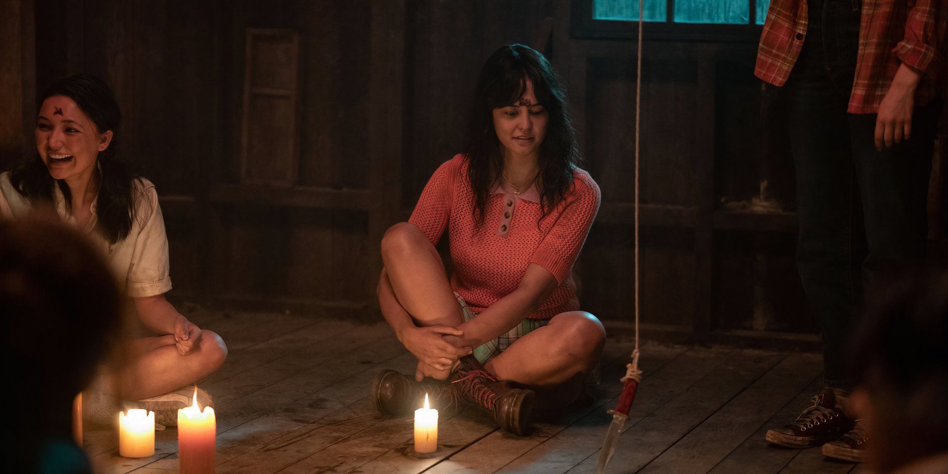 Lottie from Yellowjacket, played by actress Courtney Eaton, sits on the floor looking at a knife in Season 2.