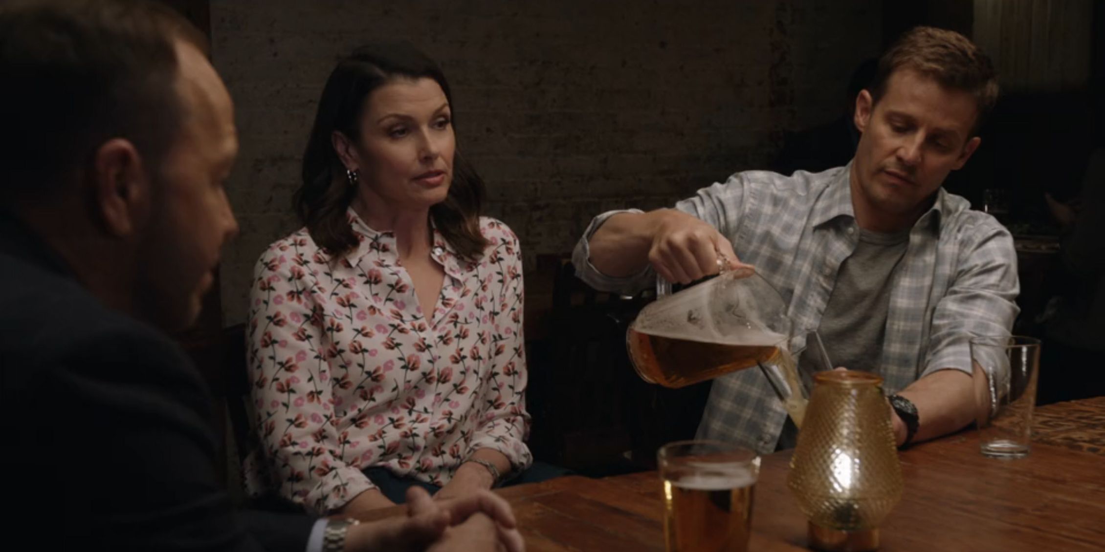 Blue Bloods Jamie pouring beer from a pitcher while sitting next to Erin at a restaurant