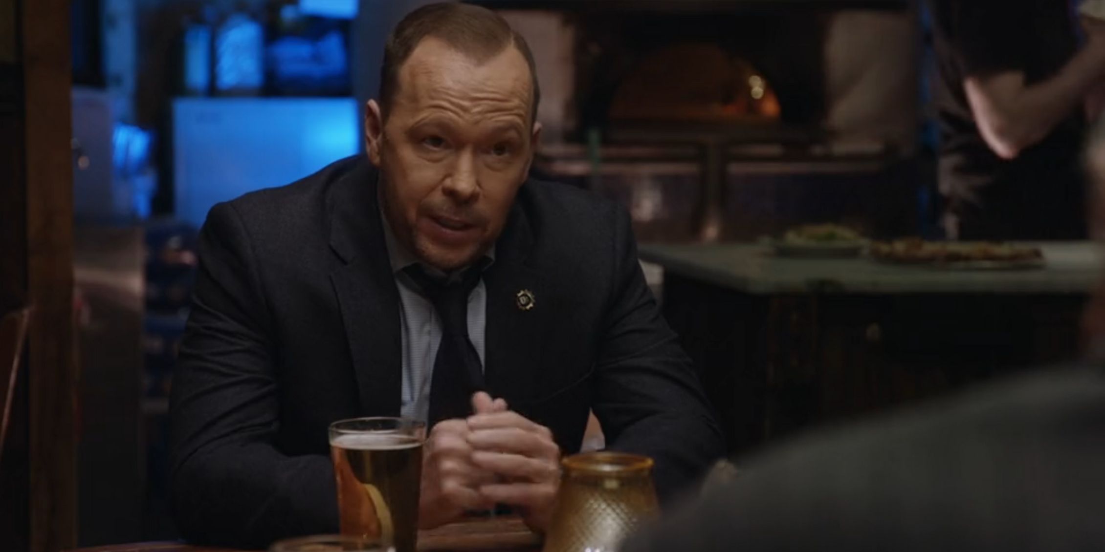 Blue Bloods Danny sitting with his hands clasped at a family dinner in a restaurant