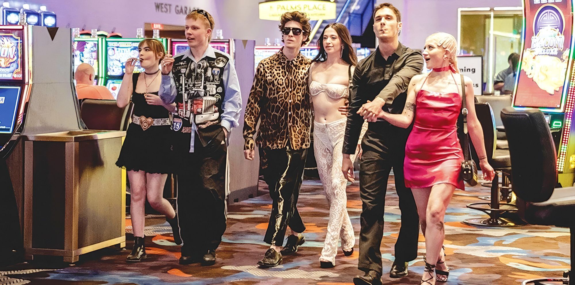 Ivan (Mark Eidelshtein) and Ani (Mikey Madison) walking through a casino with some friends in ANORA