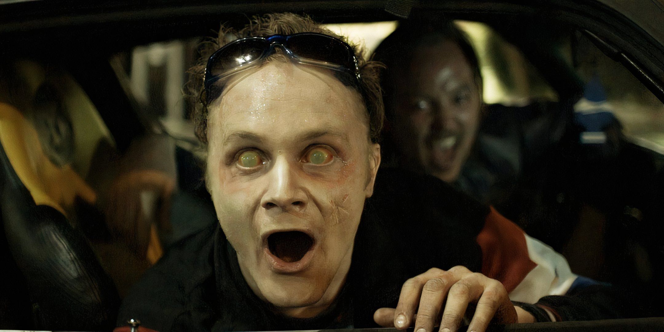 Chris Wylde and David Anders stick their heads out a car window excitedly. 