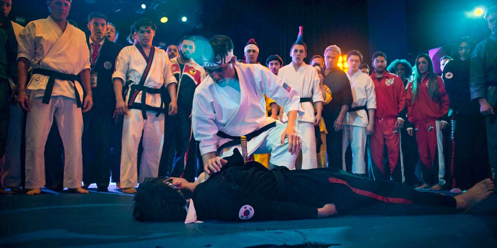 Kwon (Brandon H. Lee) lying on the mat with a dagger stabbed in his chest in Cobra Kai Season 6 Ep 10