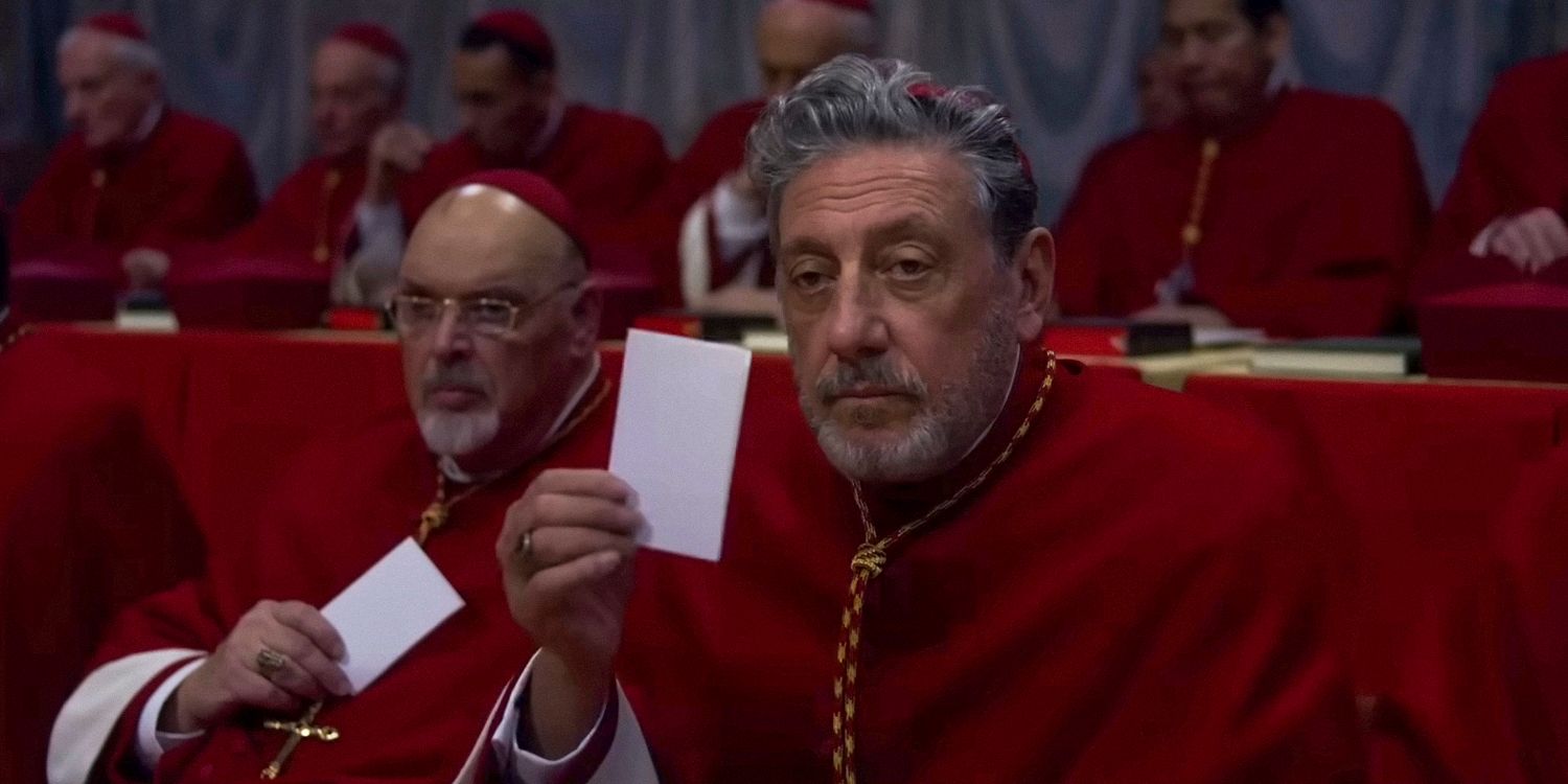 Tedesco holding up a slip of paper in Conclave