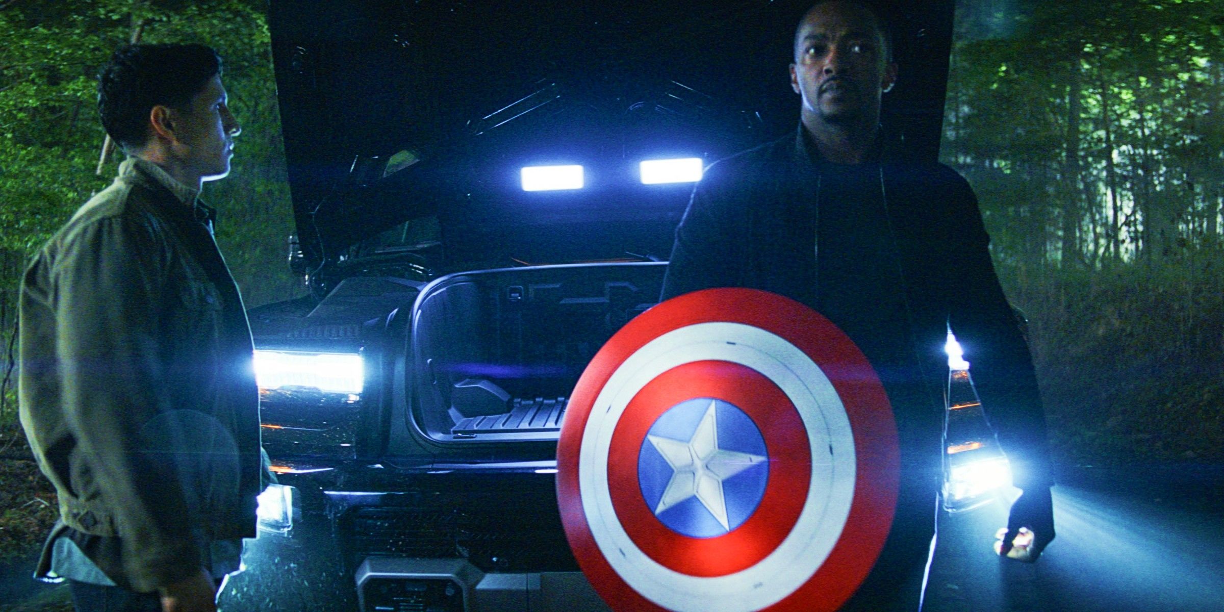 Danny Ramirez As Joaquin Torres And Anthony Mackie As Sam Wilson With The Cap Shield Near A Car In The Woods In Captain America Brave New World-1