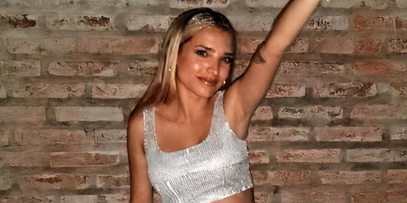 Love Is Blind: Argentina season 1 Emily Ceco in a shiny silver skirt and cropped top with one hand in the air