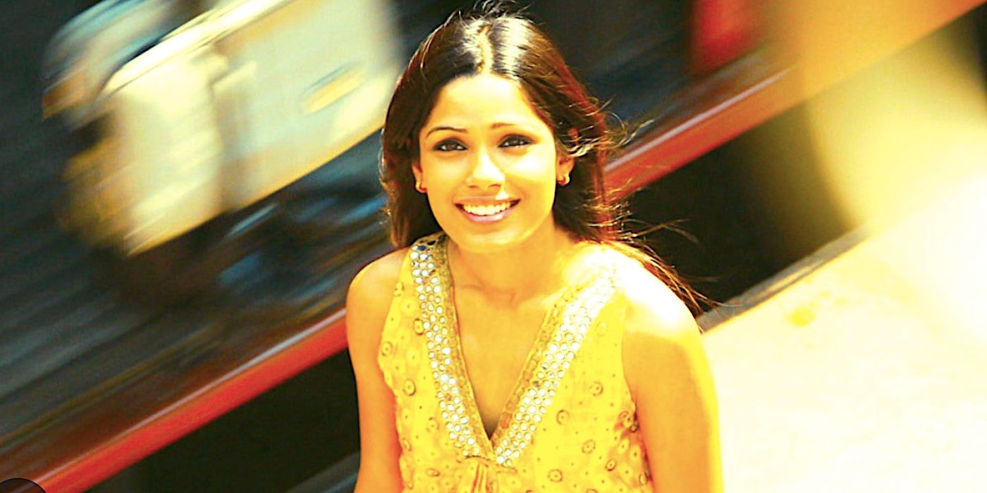 Frieda Pinto's Latika stands on the street smiling in Slumdog Millionaire