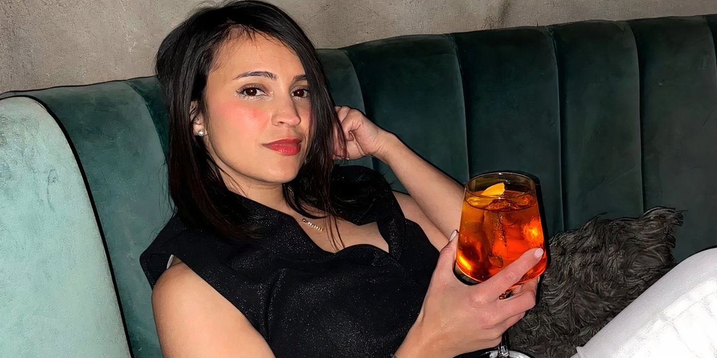 Love Is Blind: Argentina season 1 Brenda Oviedo seated on a couch holding a glass with a dress in it.