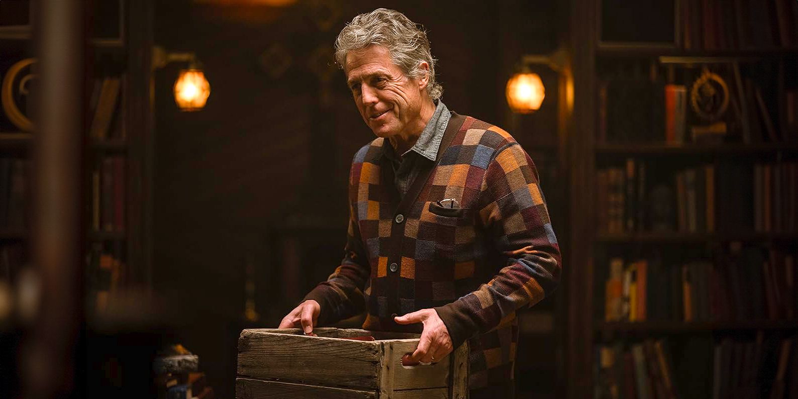 Hugh Grant as Mr. Reed smiling eagerly while holding a crate in Heretic