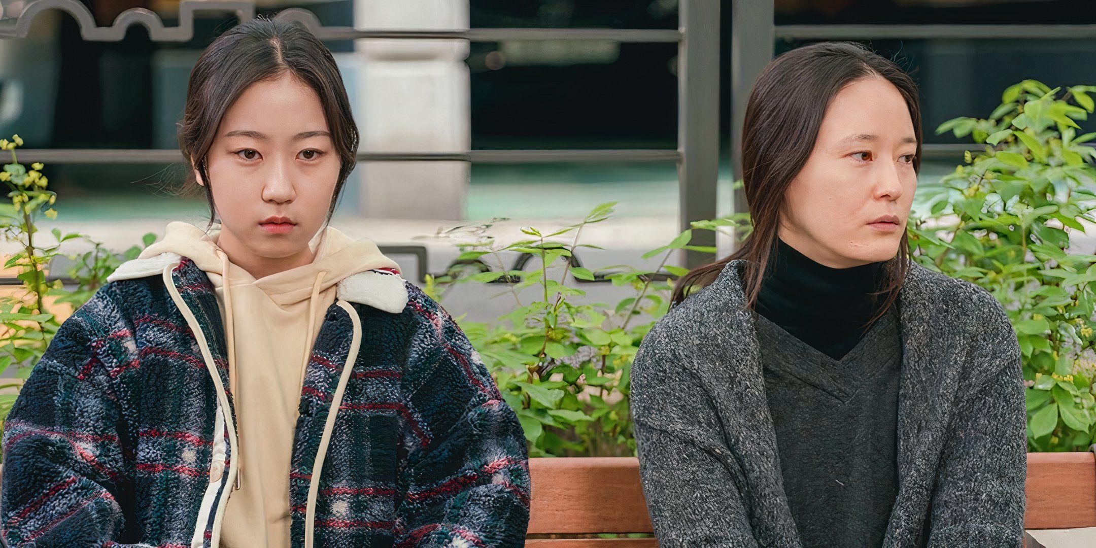 Lee Yeong-jin and Kim Hwan-hee sit next to one another on a bench. 