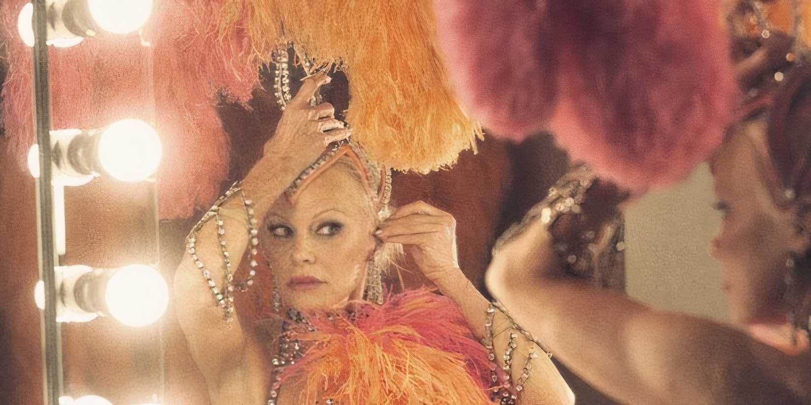 Pamela Anderson putting on a giant feather headpiece in The Last Showgirl