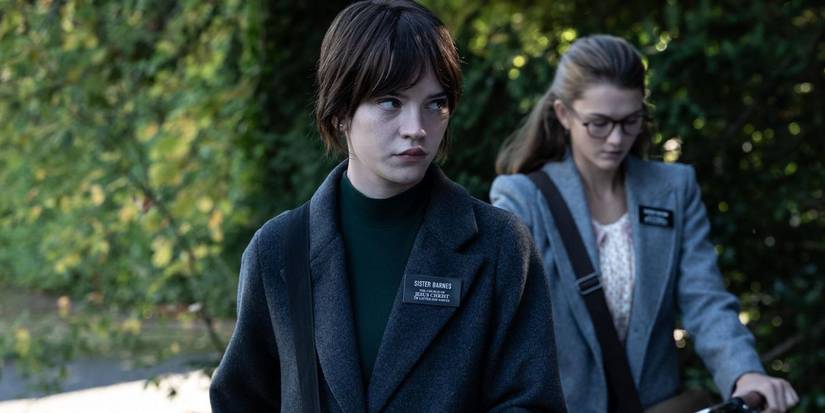 Sophie Thatcher and Chloe East walking with their bikes in Heretic