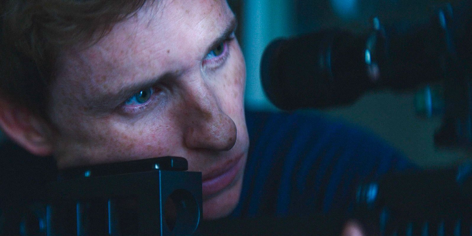 Eddie Redmayne aiming his gun at a target in Day of the Jackal