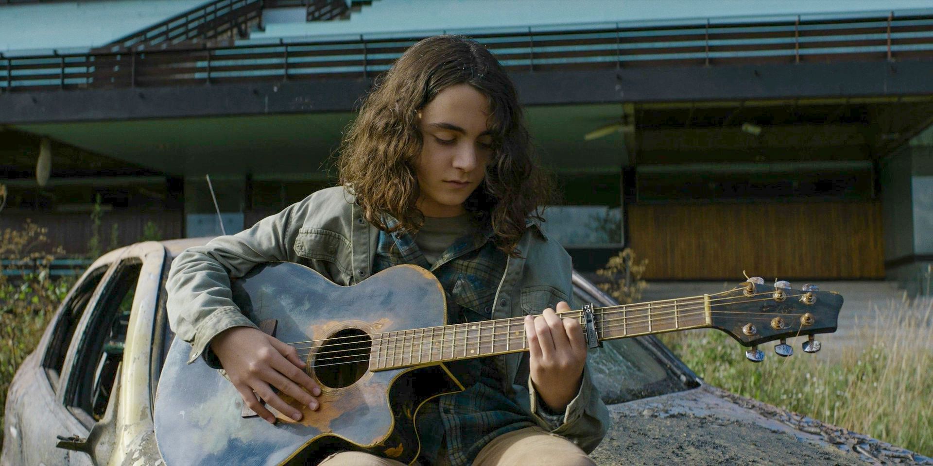 Laurent (Louis Puech Scigliuzzi) playing the guitar in The Walking Dead: Daryl Dixon.