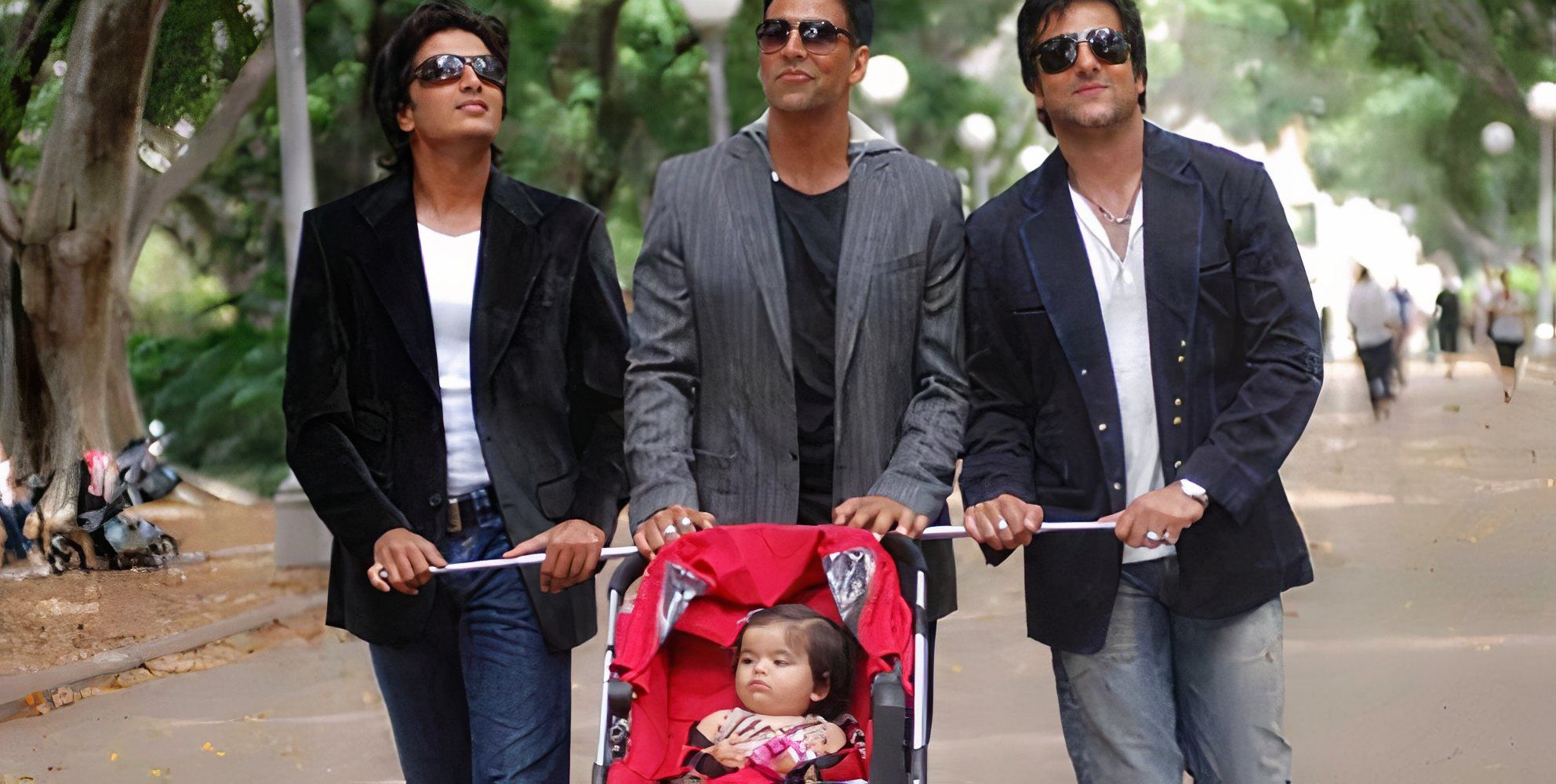 Three men all hanging on to push the same stroller in Heyy Babyy