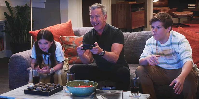 Tim Allen sitting on a couch between two kids playing video games on Shifting Gears