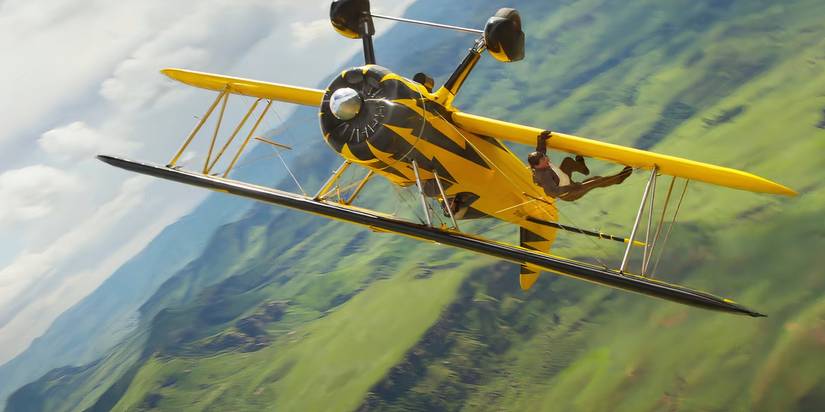 Tom Cruise hanging from a yellow biplane in Mission Impossible The Final Reckoning
