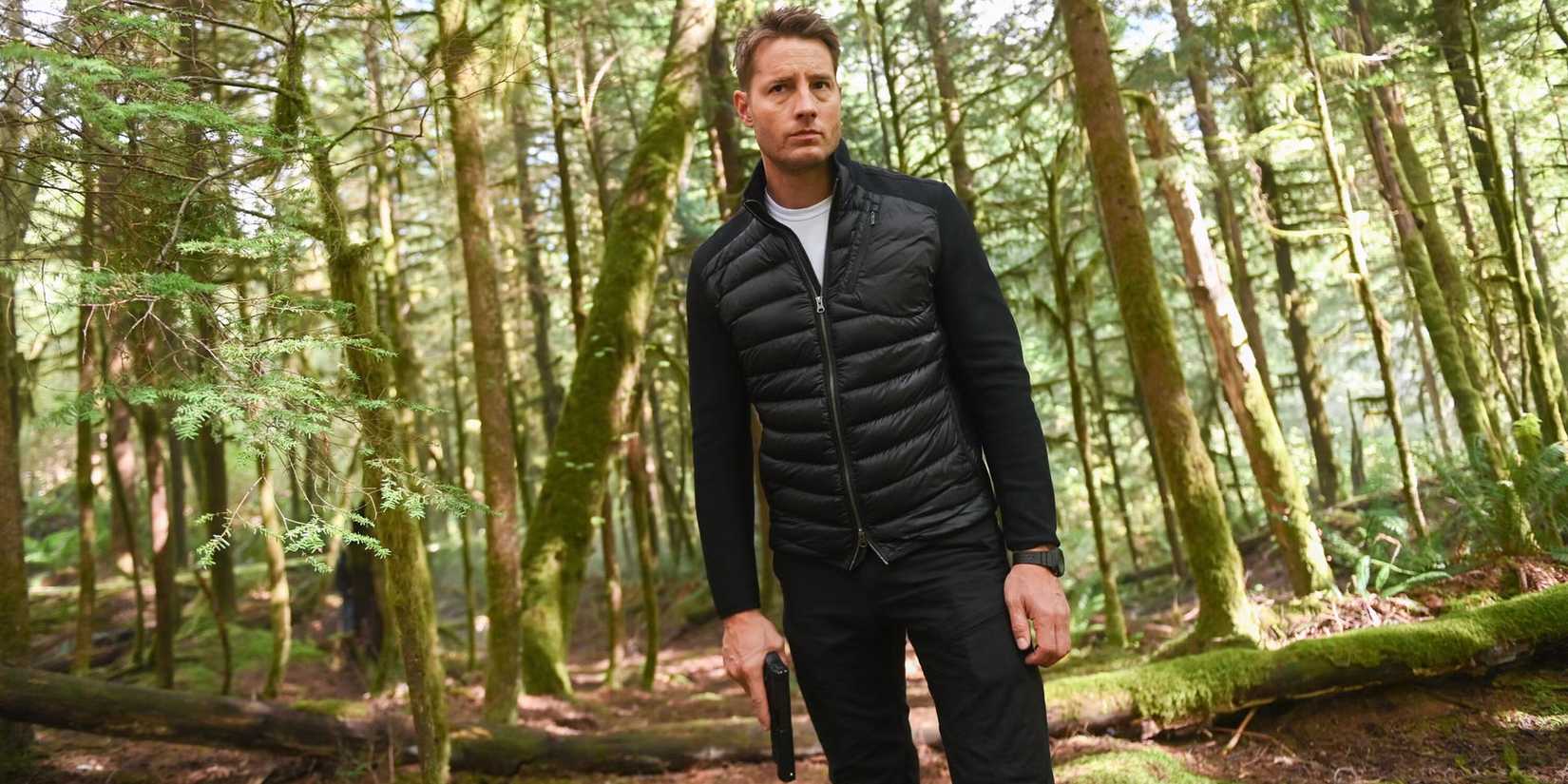 Justin Hartley as Colter Shaw standing in the woods In Tracker Season 2, Episode 6, "Trust Fall"