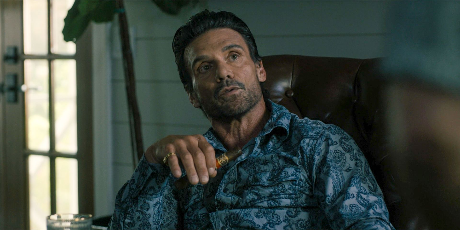 Frank Grillo holding a cigar while sitting on a couch in Tulsa King season 2 