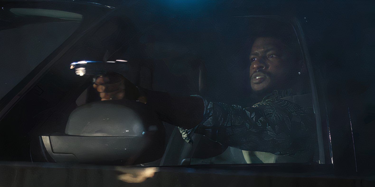 Tyson Mitchell (Jay Will) firing a pistol out the window of a car and snarling in Tulsa King season 2, episode 7