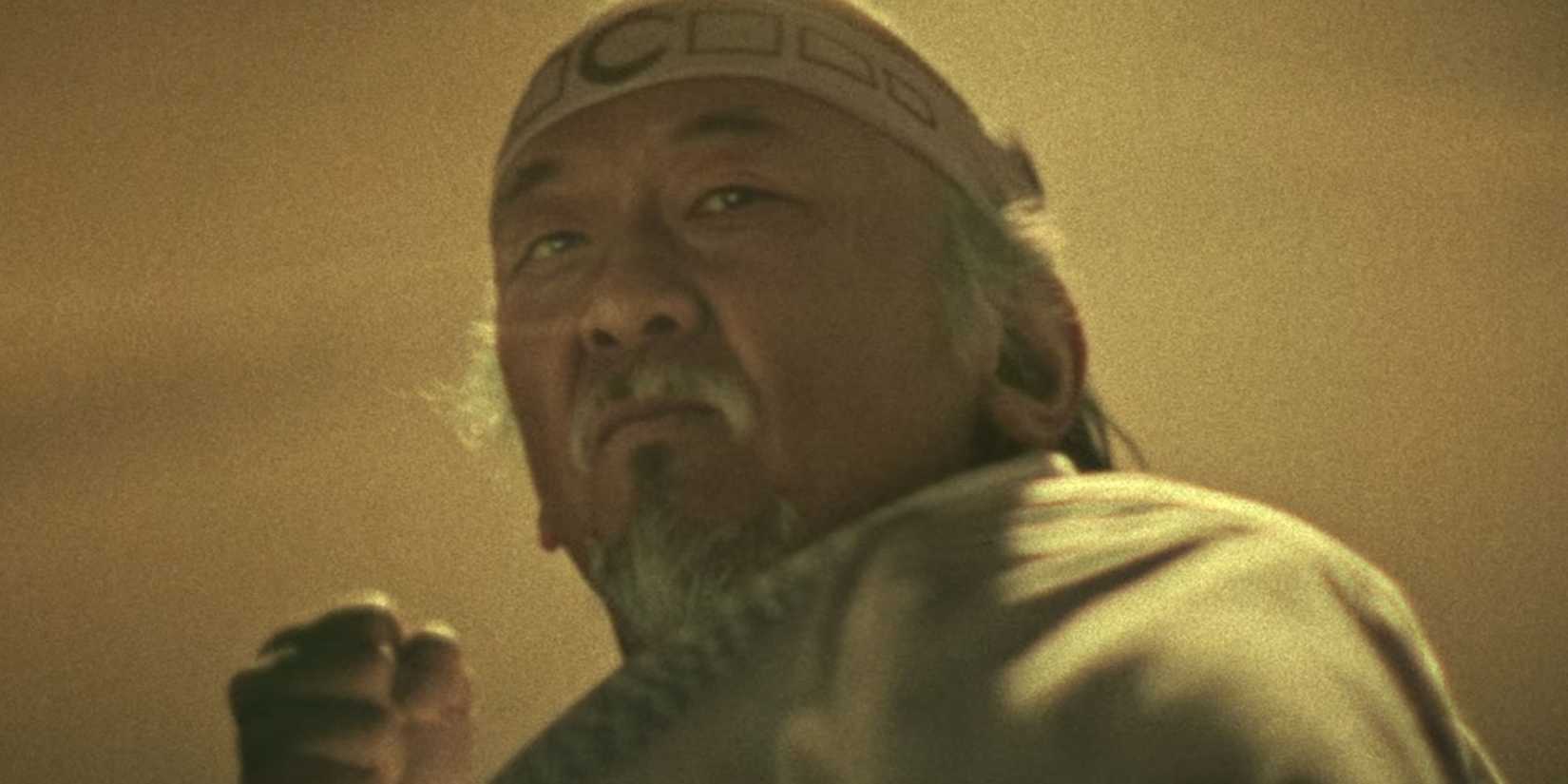 Pat Morita's Mr. Miyagi about to punch the camera in Cobra Kai